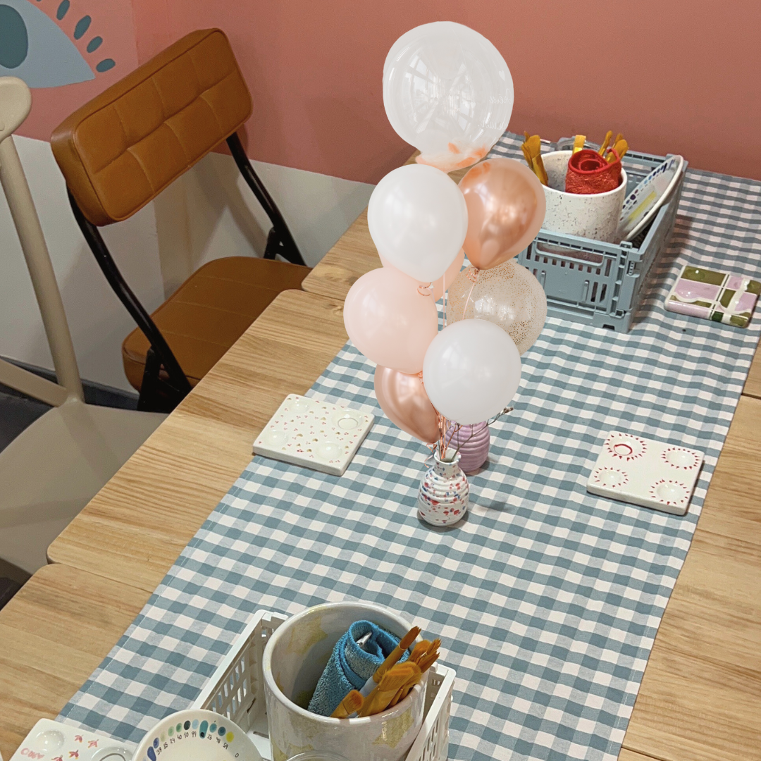 La mesa con todo lo necesario para pintar cerámica y disfrutar de un evento con globos y decoración en Mood Colors